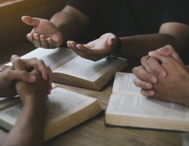 Group of christian people reading and study bible in home and pray together.Group of people holding hands praying worship god.Diverse religious shoot.